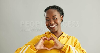 Buy stock photo Black woman, studio and heart sign for fashion with smile, sustainable or eco friendly clothes for wellness. Female person, gray background and hands with love gesture, cool portrait in New York