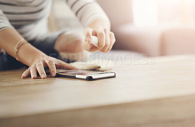 Buy stock photo Woman, hands and cleaning screen of a phone on a wooden table in a home living room with spray bottle. Closeup of a female person with cloth and product to clean dirt, bacteria or dust on smartphone