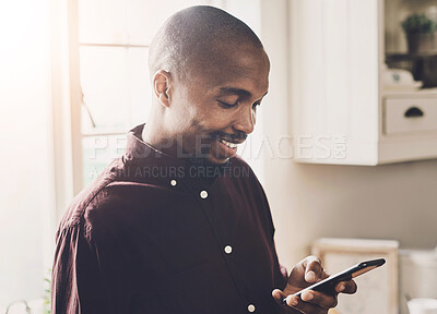 Buy stock photo Shot of a handsome young businessman using a cellphone  while working from home during the day