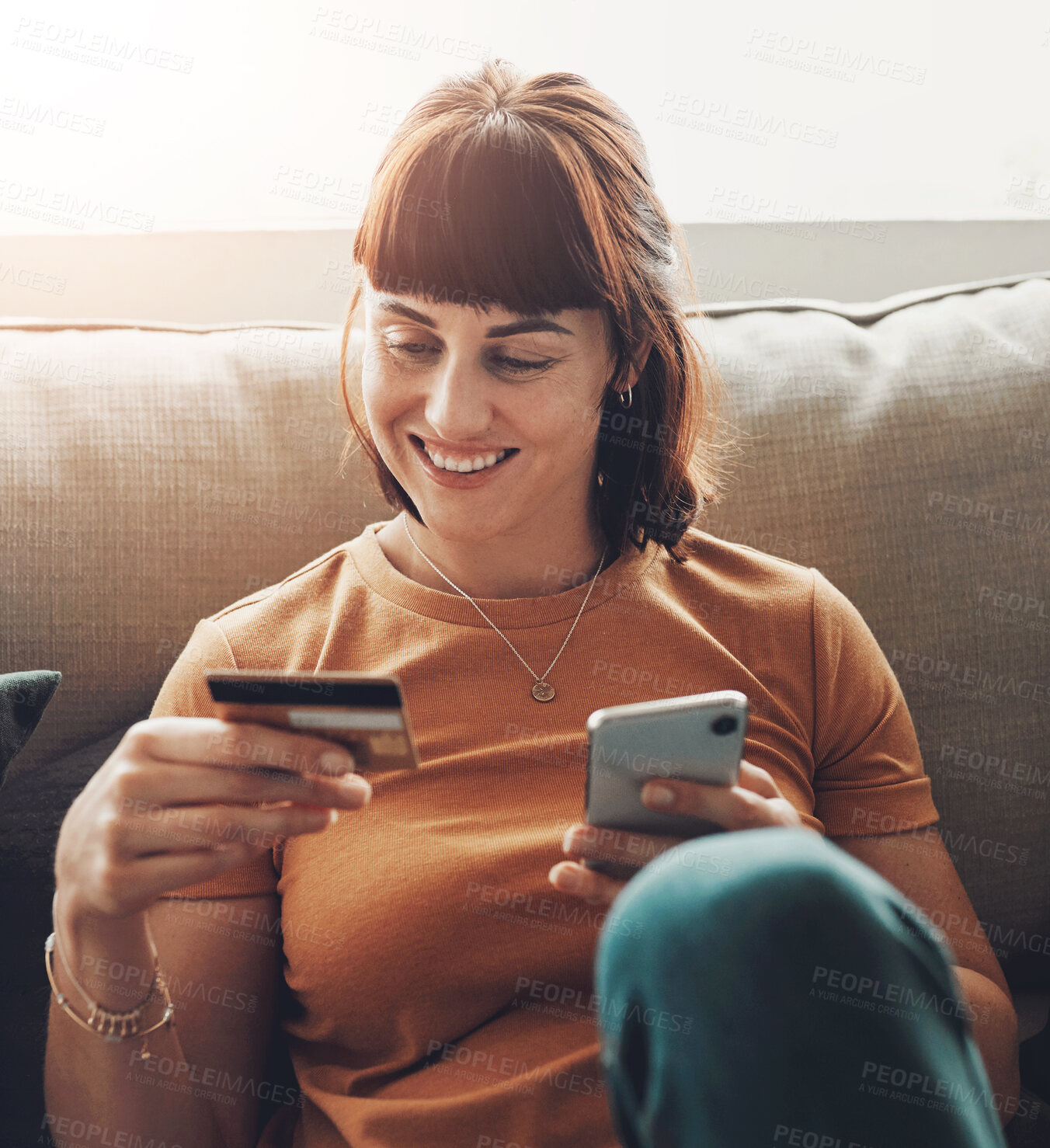 Buy stock photo Shot of a young woman holding her credit card while using her cellphone