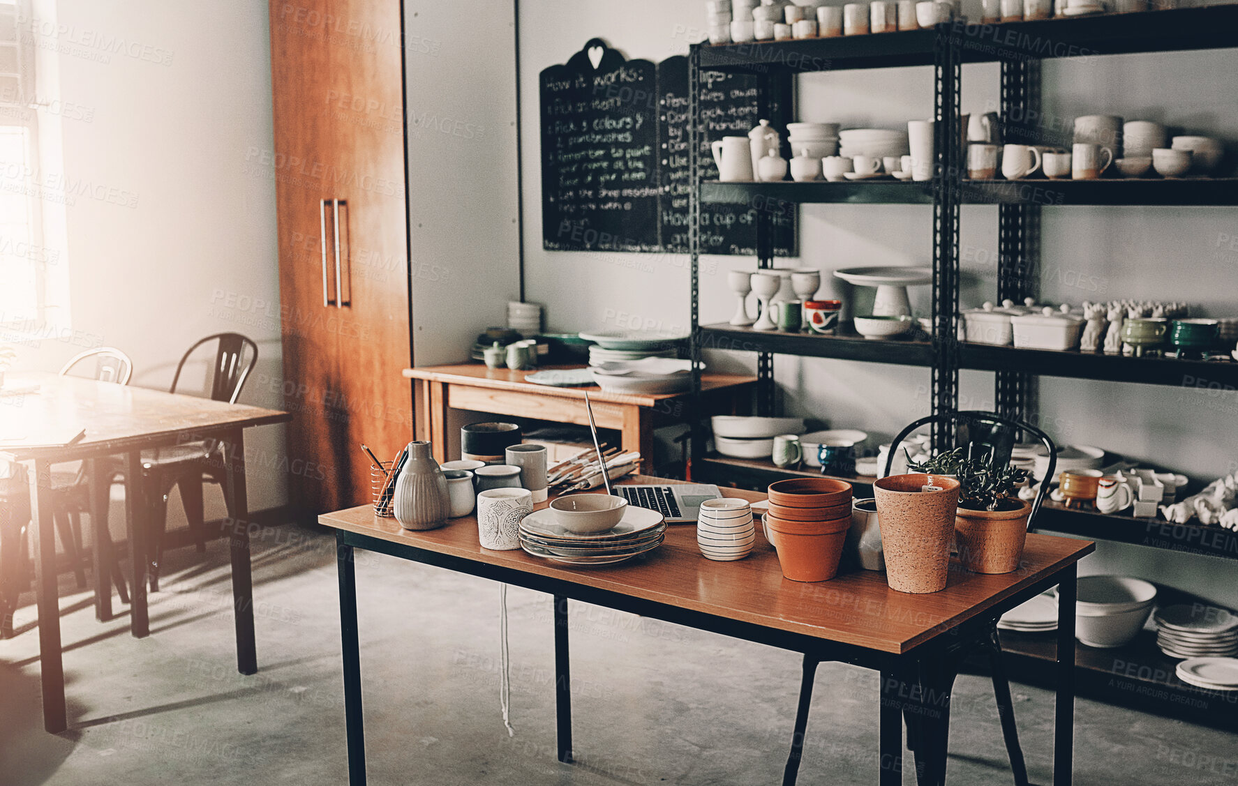 Buy stock photo Cropped shot of a potter's desk and her collection on a shelf in her empty workshop during the day