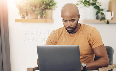 Buy stock photo Shot of a young man using his laptop while sitting on the sofa at home