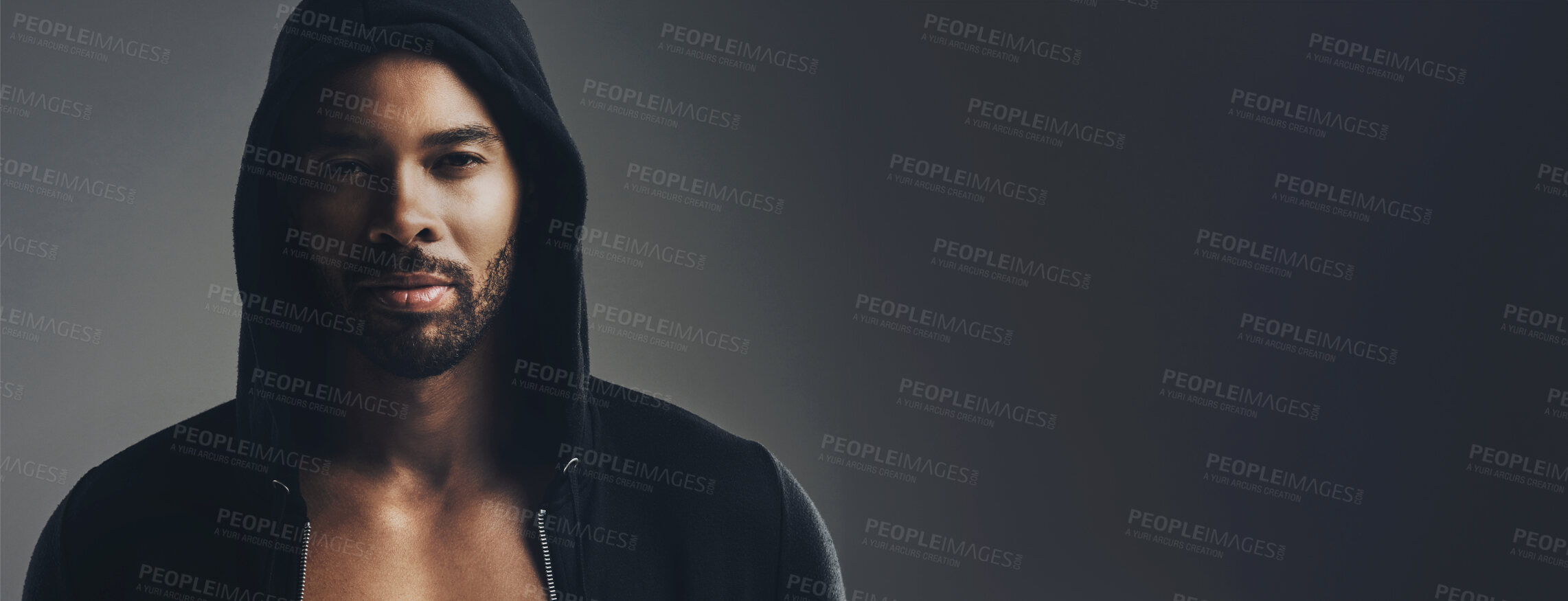 Buy stock photo Portrait of a handsome young man wearing a hoodie posing against a grey background