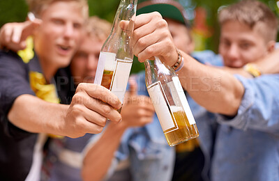 Buy stock photo Cropped shot a group of young men toasting with beer bottles