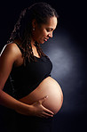 Pregnant, mom and care with stomach in studio, baby bump and woman in pregnancy. Black background, gestation and gynecology for belly growth, maternity wellness and motherhood for family planning