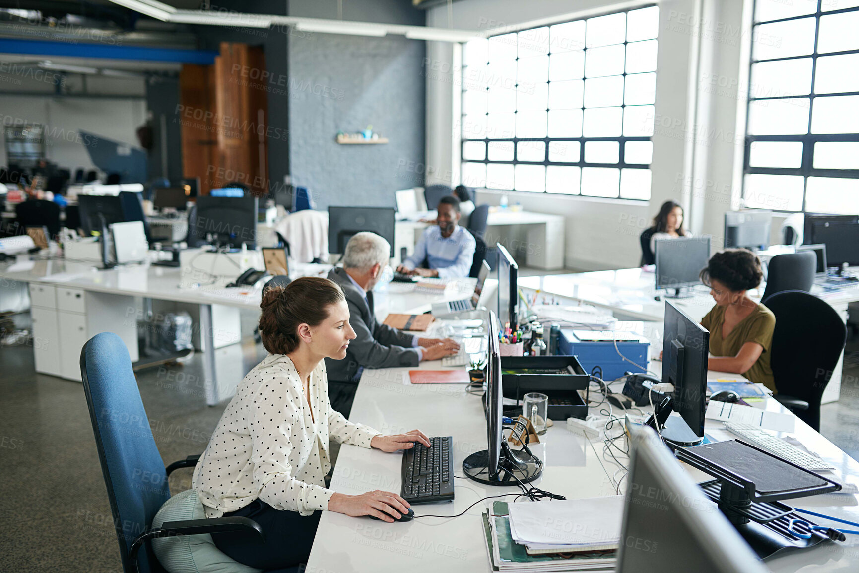 Buy stock photo Shot of colleagues working on their computers while sitting in an office