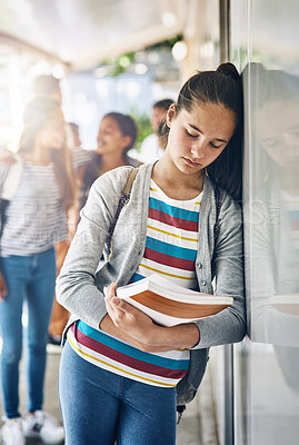 Buy stock photo Shot of a lonely schoolgirl standing outside her classroom with classmates in the background