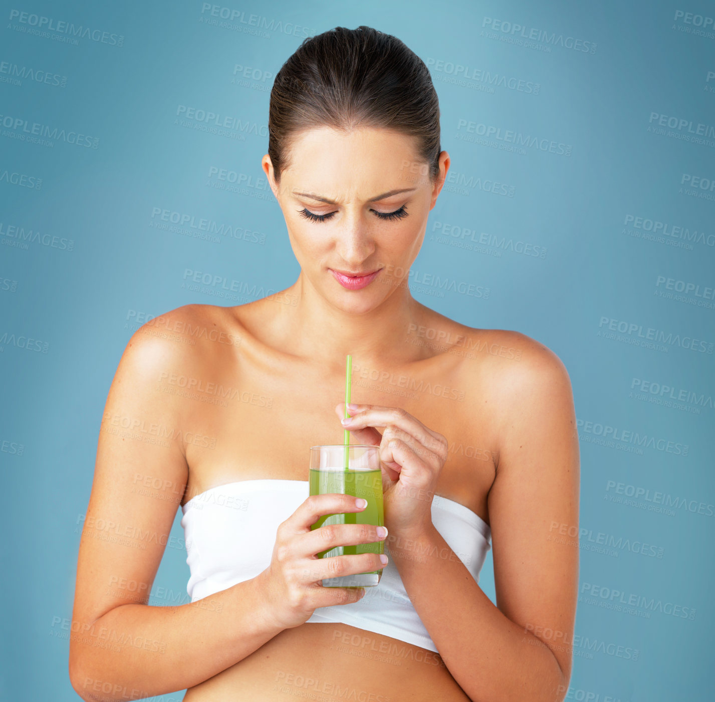 Buy stock photo Woman, green smoothie and unhappy detox in studio, weight loss beverage and blue background. Female person, laugh and organic juice or raw shake for nutrition, vitamin and vegan supplement for health