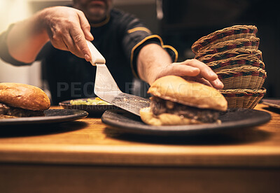 Buy stock photo Chef, person and hands in kitchen with hamburger, fast food and preparation on table. Male cook, meal and dinner of sandwich, order and culinary for hospitality service with cooking for professional