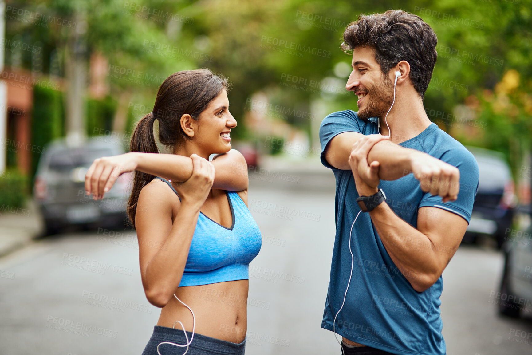 Buy stock photo Stretch, couple and street for workout, earphones and music for cardio or run club. Arm, fitness and warm up for training together and smile for married people, exercise and marathon preparation 