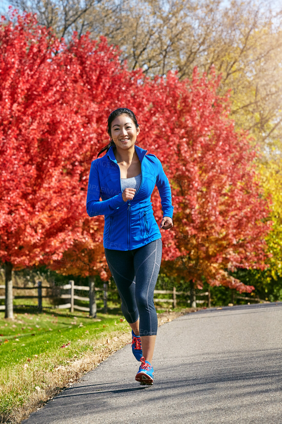 Buy stock photo Nature, asian woman and running with fitness and happy for cardio workout, training or outdoor exercise in countryside. Active female person, athlete or runner with smile for sprint on road in autumn