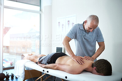 Buy stock photo Man, back pain and physiotherapist working in consulting room, rehabilitation with exercise for wellness. Male people, office and together for physiotherapy service with health insurance or support