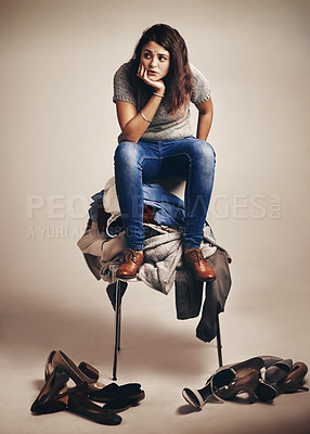 Buy stock photo Fashion, upset and woman with pile of clothes on chair for mess, clutter or collection. Doubt, uncertain and female shopaholic with chaos of clothing for outfit choice isolated by studio background.