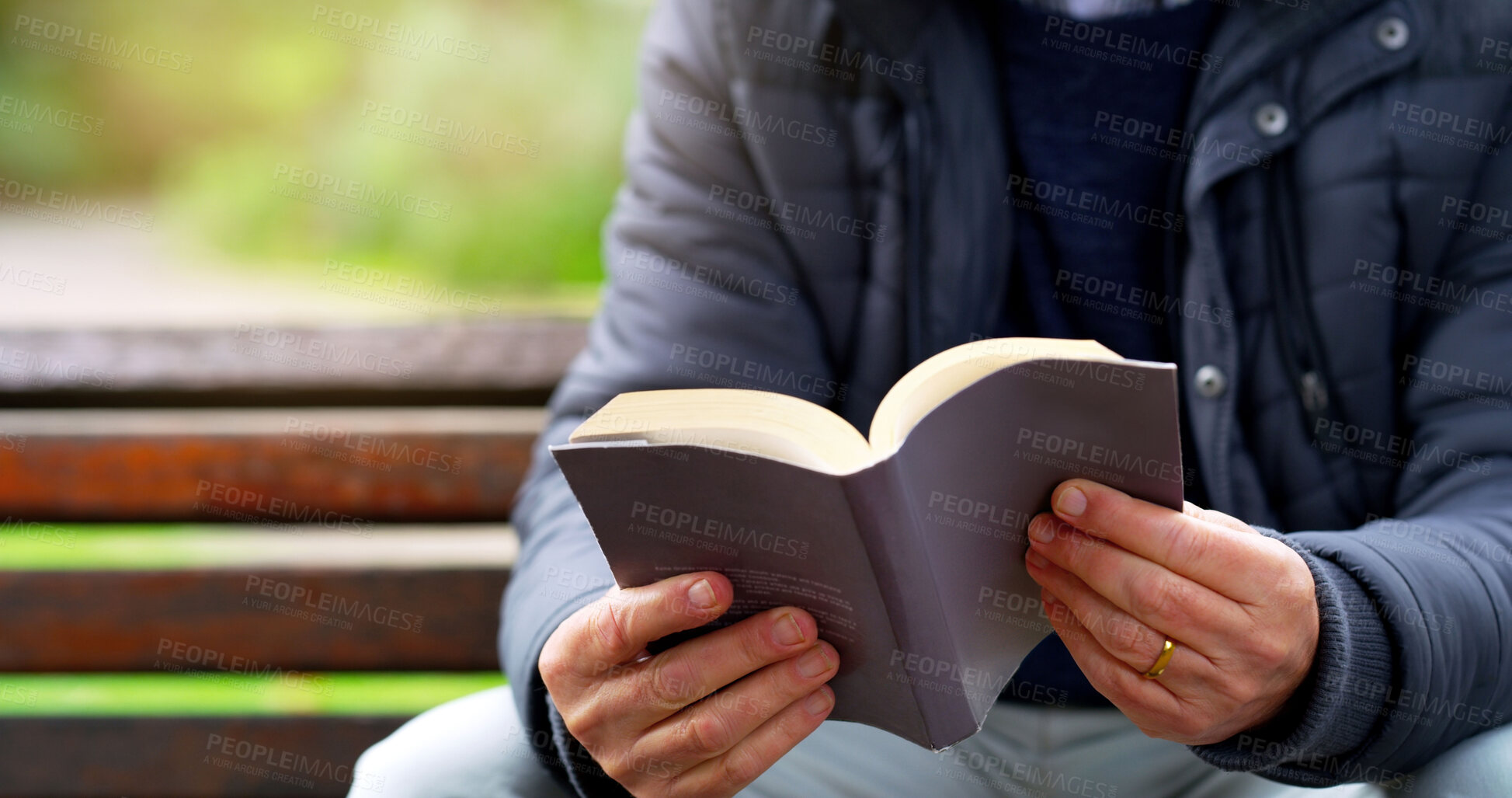 Buy stock photo Cropped shot of an unrecognizable elderly man reading a book by herself outside in a park