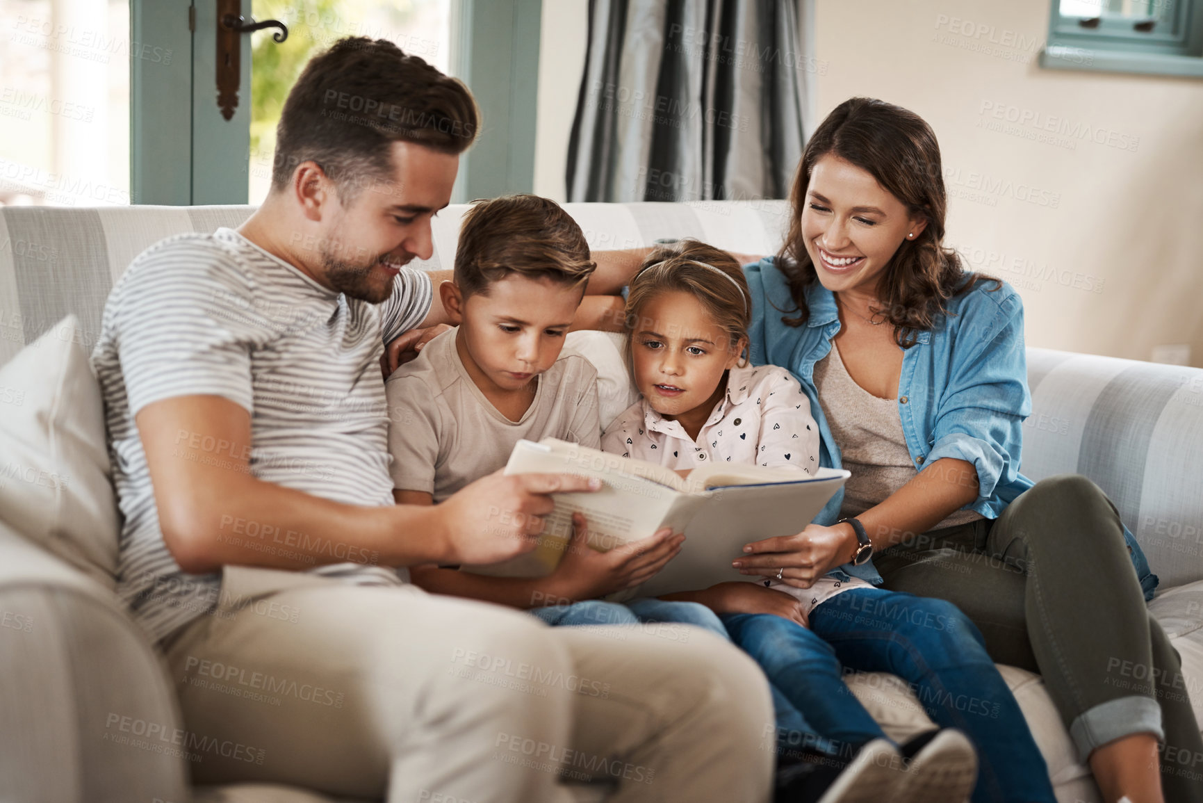 Buy stock photo Parents, children and book for story on sofa with care, bonding and happy for learning in family home. Father, mother and kids with love, connection and reading for development on couch in Madrid