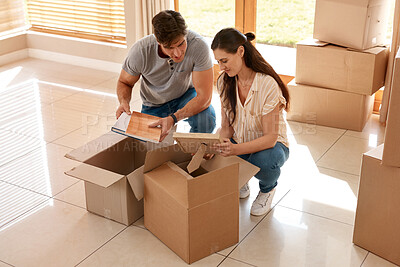 Buy stock photo Shot of a couple unpacking boxes in their new home