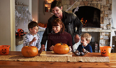 Buy stock photo Shot of an adorable young family carving out pumpkins and celebrating halloween together at home