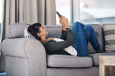 Buy stock photo Relax, phone and happy woman on sofa with glasses for reading, social media or web communication in her home, Smartphone, app and girl person in living room with gif, chat or online games in a house