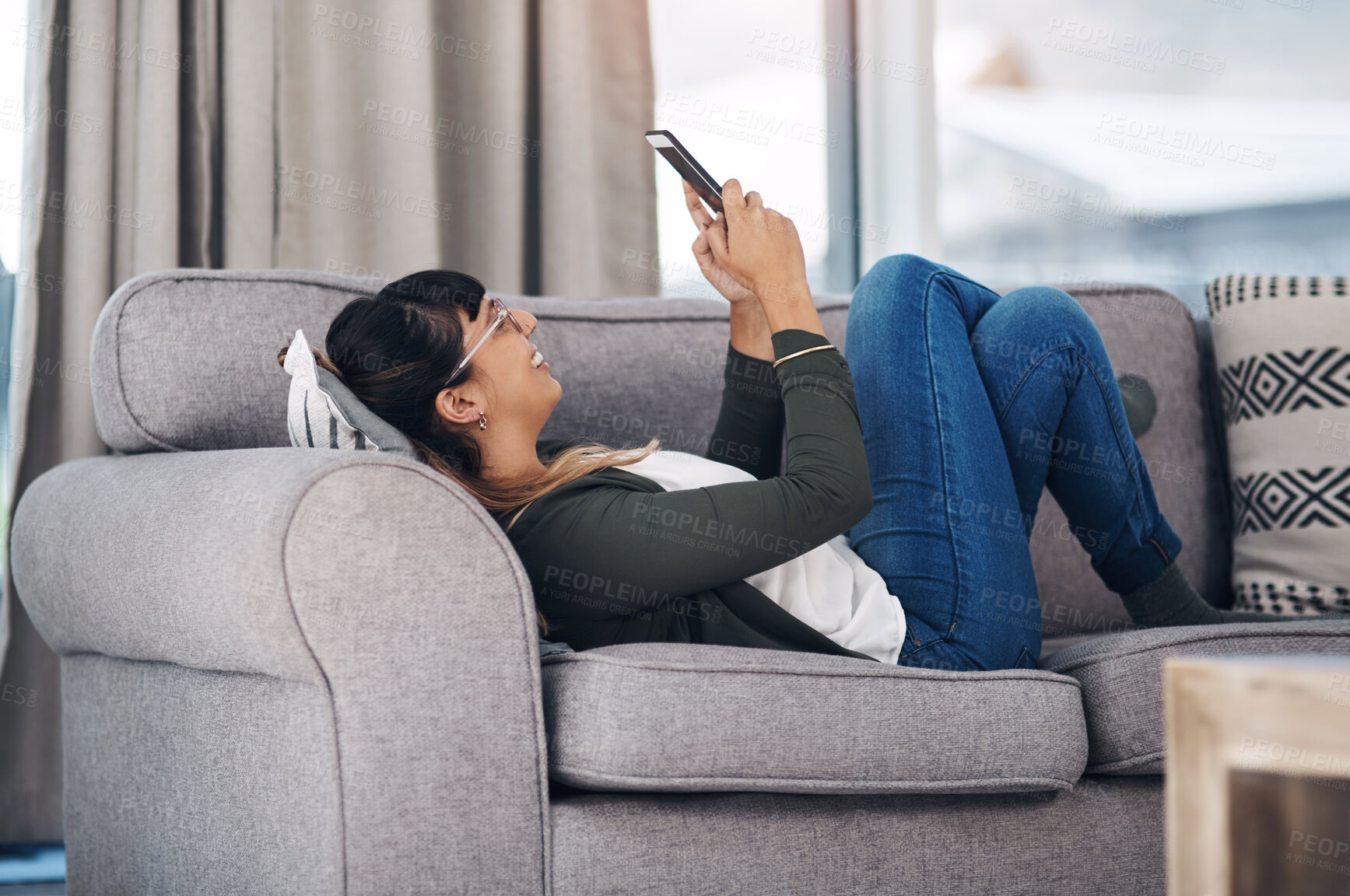 Buy stock photo Relax, phone and happy woman on sofa with glasses for reading, social media or web communication in her home, Smartphone, app and girl person in living room with gif, chat or online games in a house