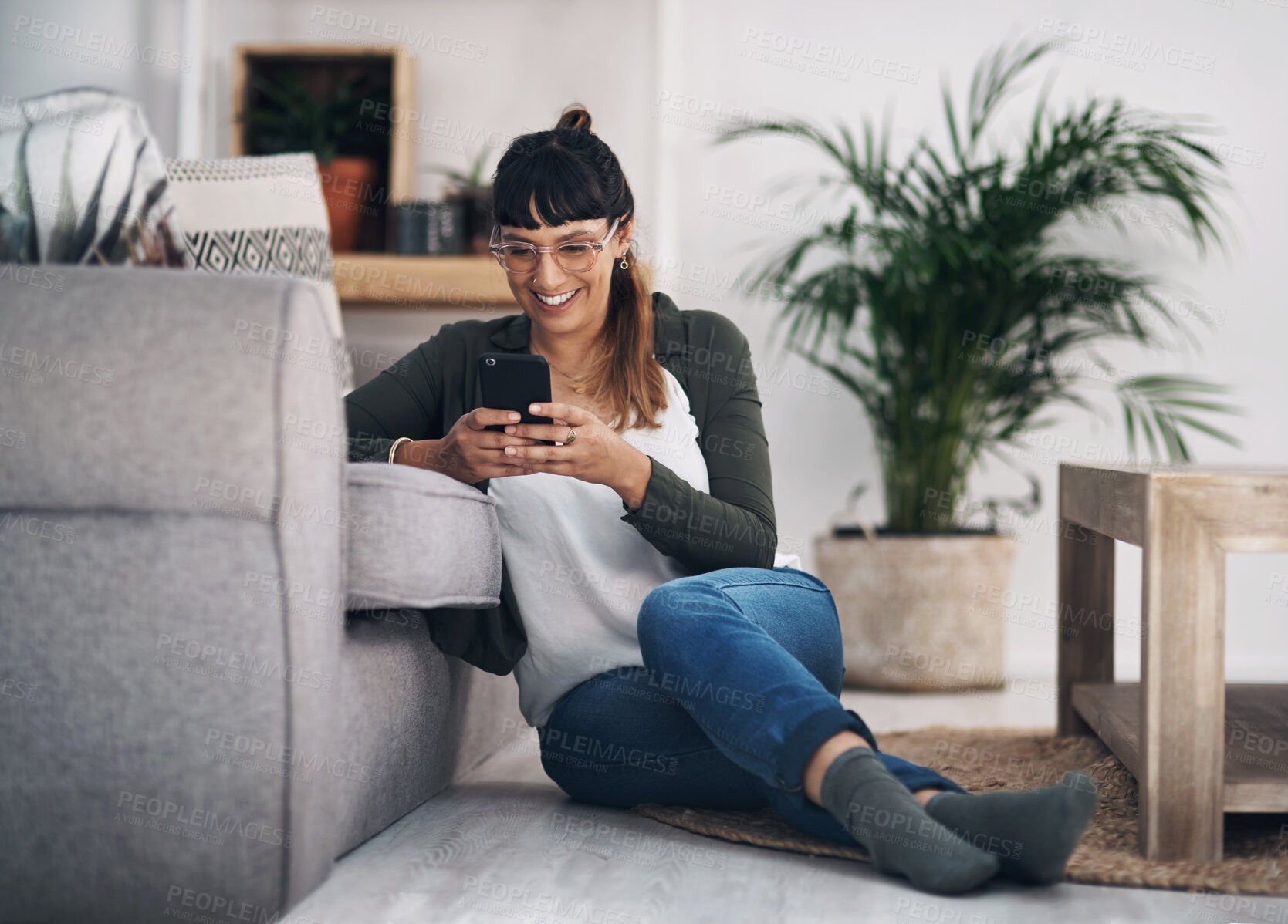 Buy stock photo Woman, phone and home on floor for texting with contact on mobile app for communication in lounge. Person, smartphone and happy for meme, video or web chat on social network at house in Colombia