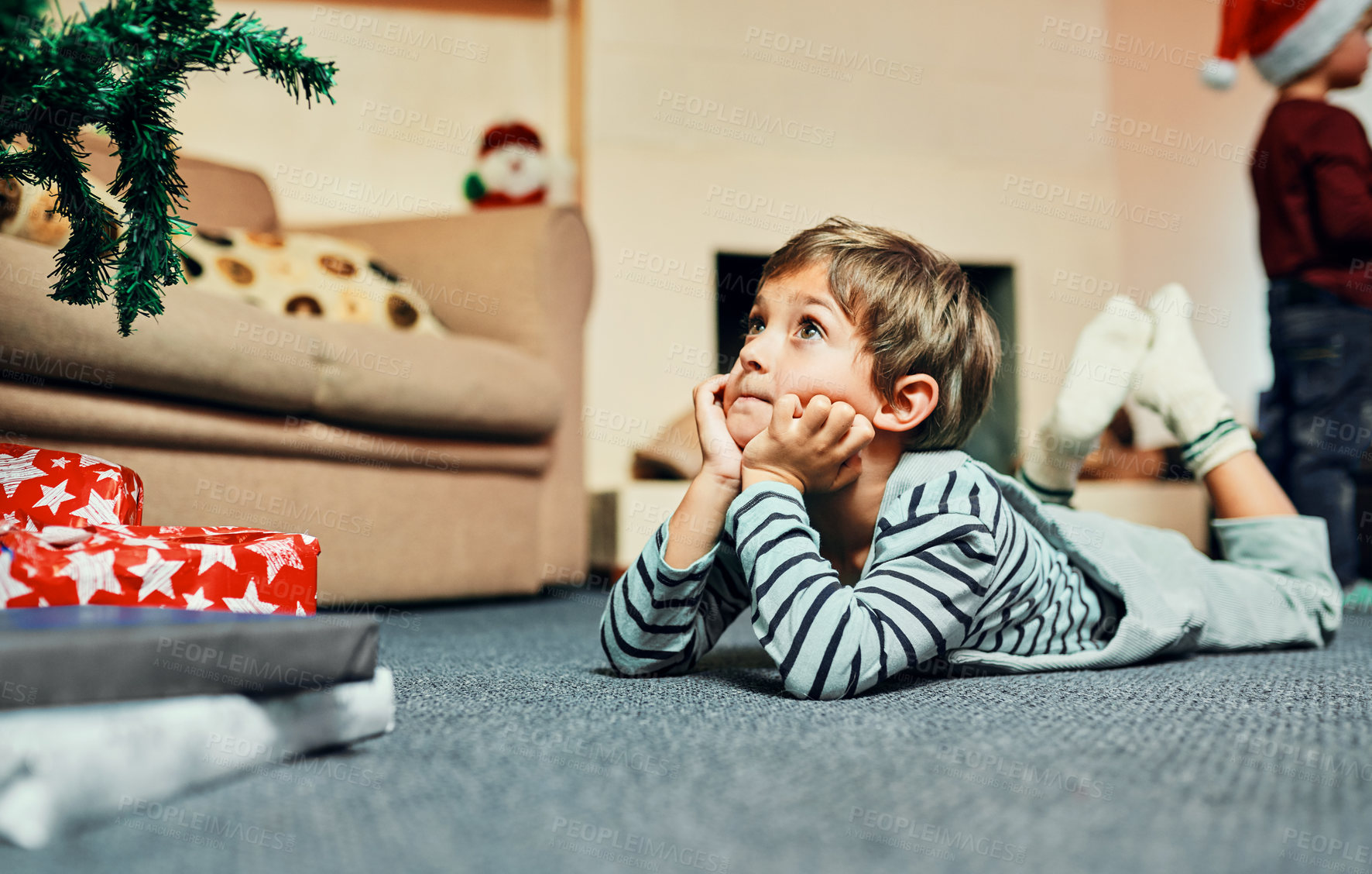 Buy stock photo Christmas tree, gift and boy waiting to celebrate winter holiday, vacation or joyful time in home or house. Kid, development and child lying on carpet, ground or floor to relax in xmas festive season