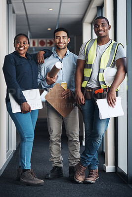 Buy stock photo Shot of a group of architects standing together and holding floor plans in a room before renovation