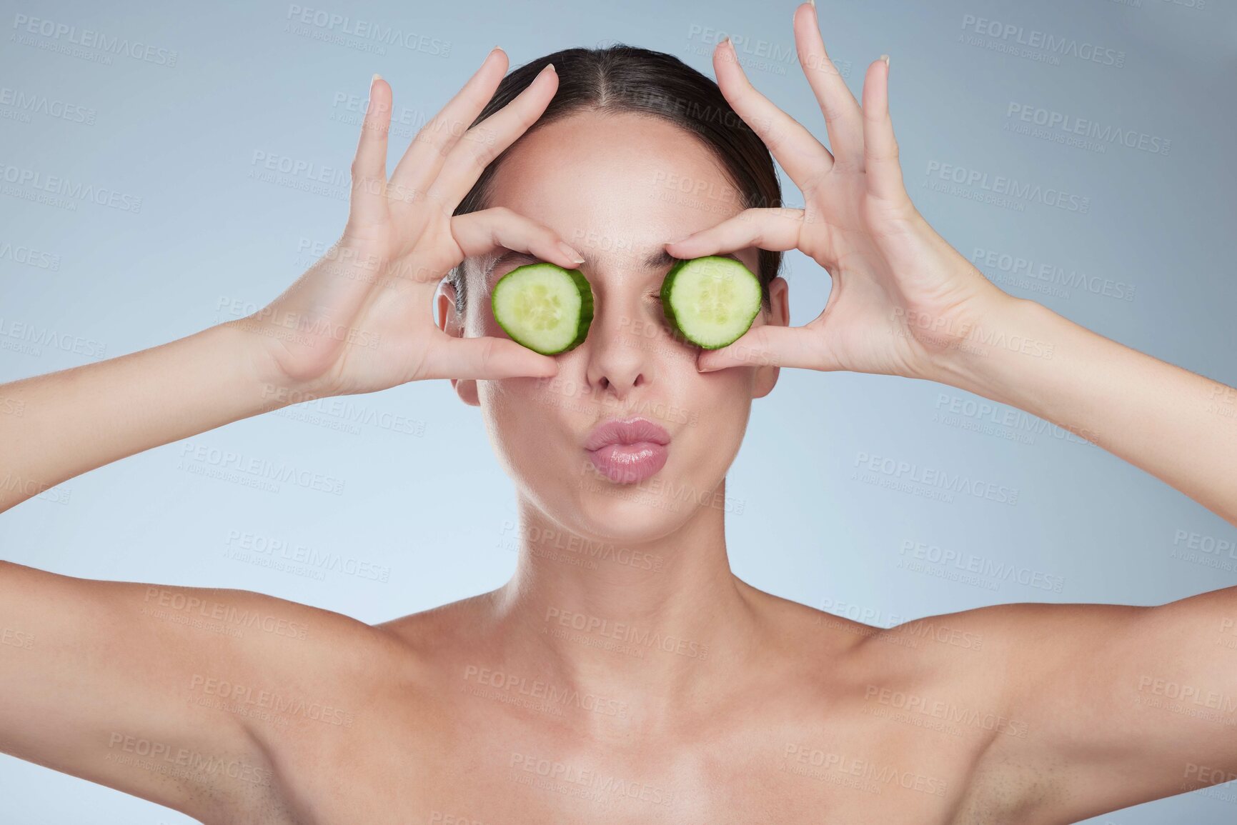 Buy stock photo Woman, cucumber eyes and organic skincare in studio, vegan beauty and pout on blue background. Female person, natural cosmetics and facial treatment or eyecare, sustainable dermatology and detox