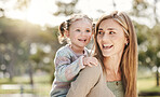 Happy single mother giving her little daughter a piggyback ride outside in nature. Smiling caucasian single parent bonding with her adorable child at the park. Playful kid enjoying free time with mom