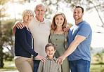 Portrait of a smiling multi generation caucasian family standing close together outdoors. Adorable little boy bonding with his mother, father, grandfather and grandmother at a park