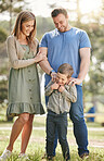 Young happy caucasian family relaxing and standing  together in nature. Loving parents spending time with their little son at the park. Carefree child bonding with mom and dad