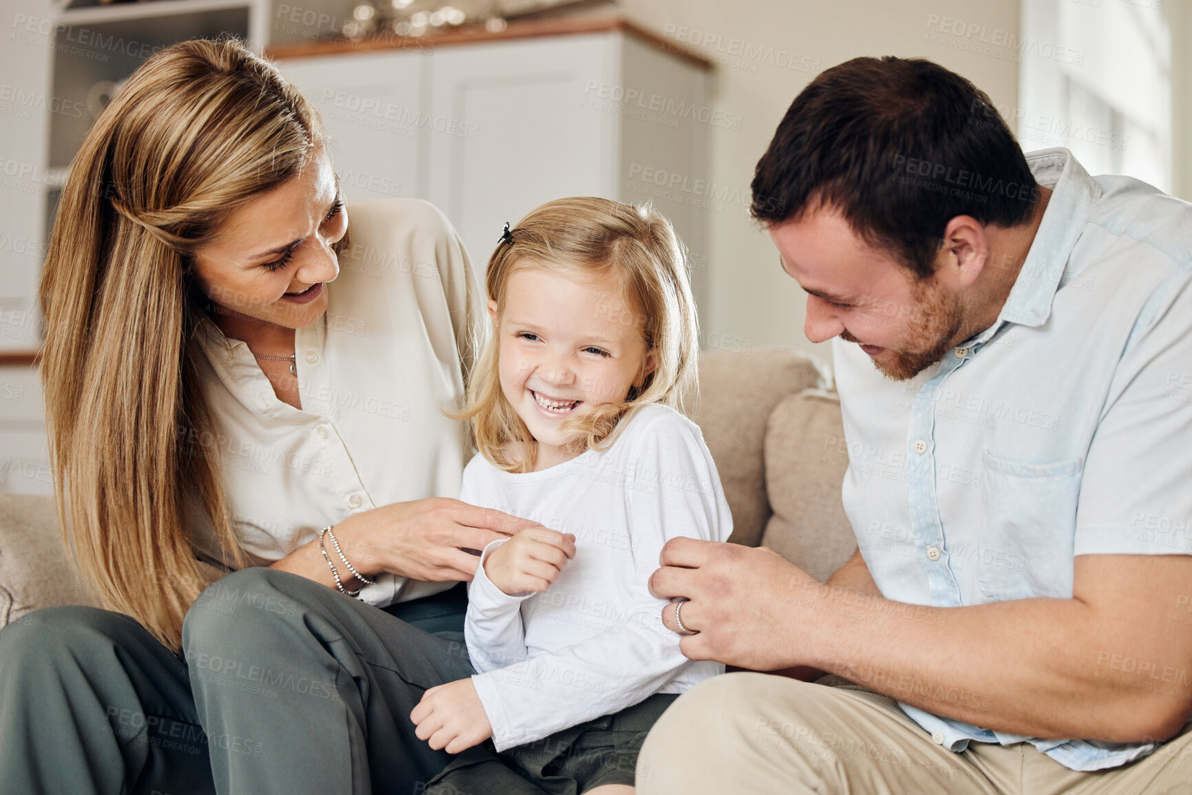 Buy stock photo Home, family and child with laughing at tickle for playful bonding, funny and love on weekend. Sofa, mother and father with daughter in living room for silly joke, humor and parenthood happiness