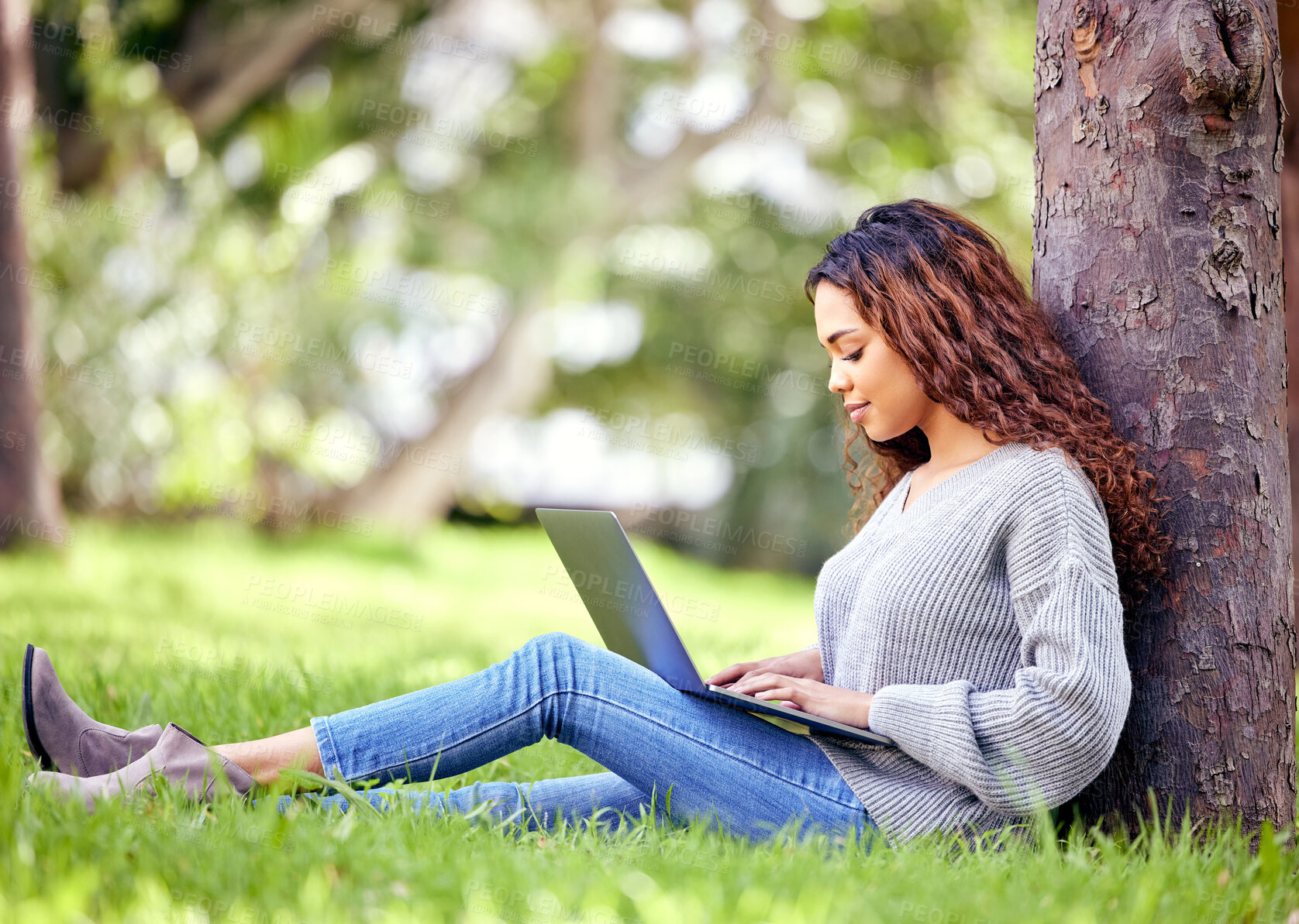 Buy stock photo Woman, student and typing on laptop at a park outdoor for education, research or studying. African person at university or college campus tree in nature with tech for knowledge, internet and learning