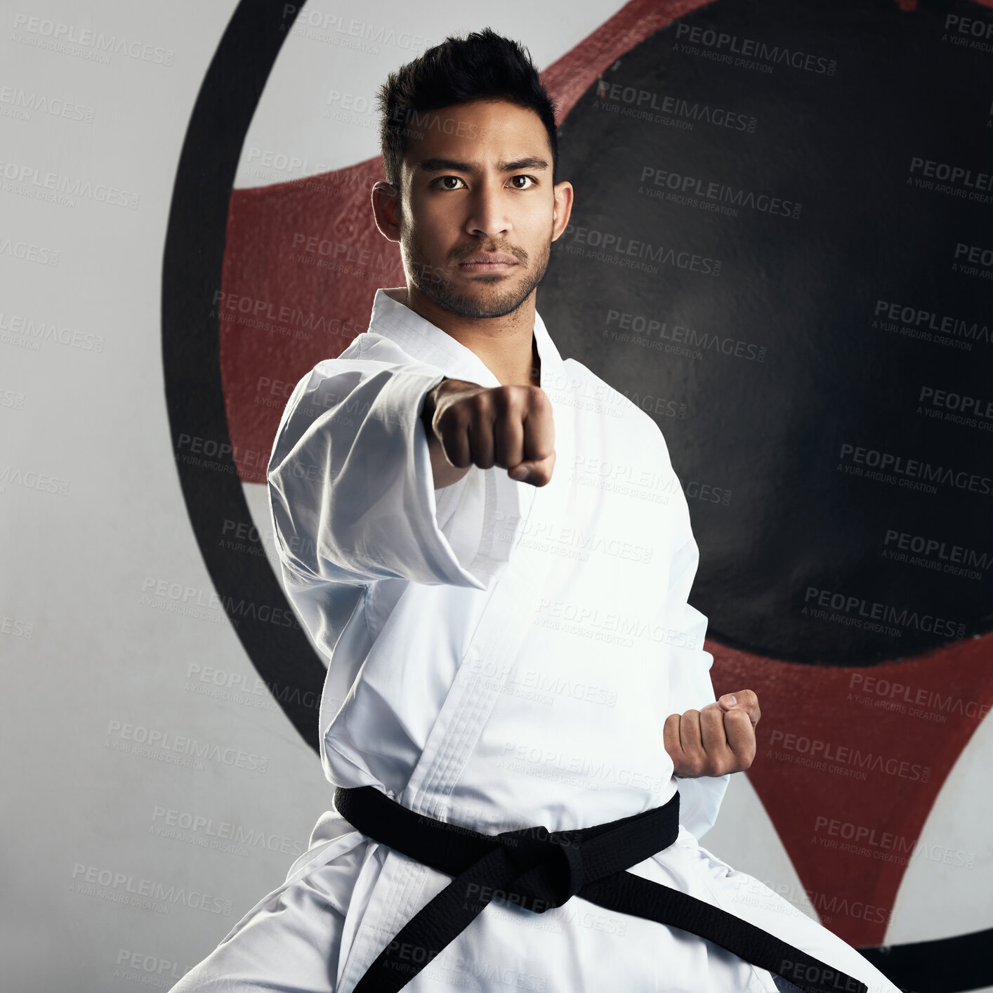 Buy stock photo Cropped portrait of a handsome young martial artist practicing karate in his dojo