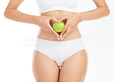 Buy stock photo Heart hands, apple and stomach in studio for diet, wellness and choice for nutrition by white background. Person, body and fruit for gut health, decision and vegan food to lose weight for change