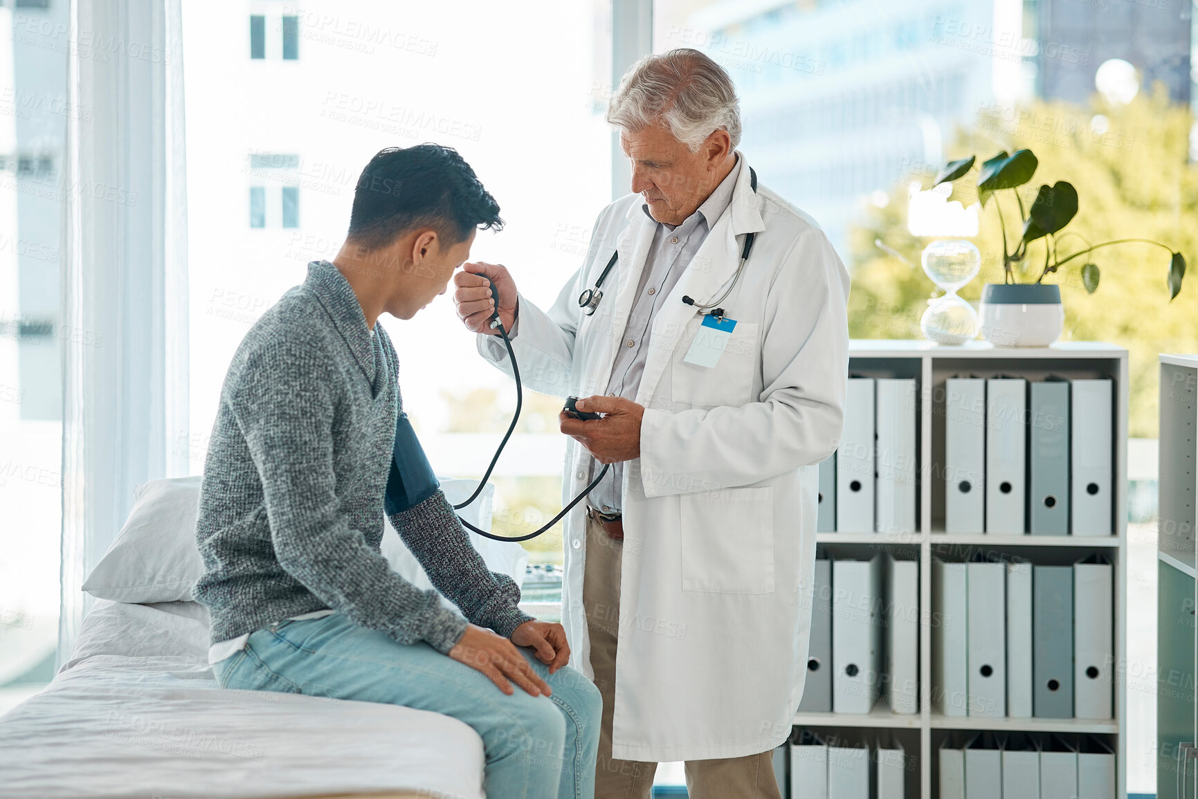Buy stock photo Mature doctor, patient and pressure gauge for consultation in hospital bed for examination and hypertension. People, medical service and healthcare tools for checkup, wellness and support with care