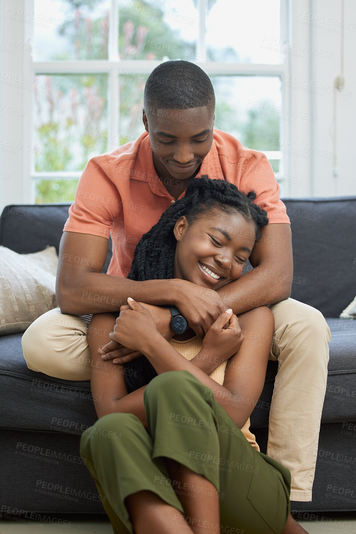 Buy stock photo Love, happy and black couple hug in lounge to relax, smile or enjoy anniversary together for peace or trust. Couch, romantic woman and man bonding in apartment for care, support or special moment