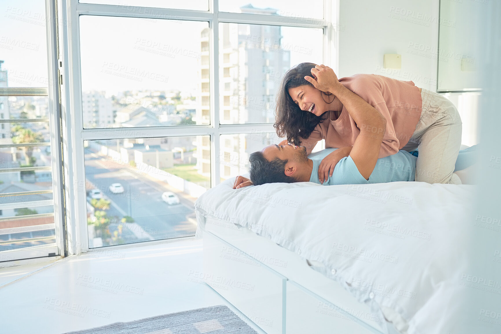 Buy stock photo Couple, laugh or bed in hotel for love, romance or vacation for anniversary. Man, woman or bonding in guest house bedroom for trust, commitment or passion on holiday for milestone celebration in city