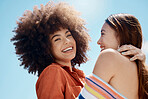 Portrait of two young mixed race female friends embrace and smiling outside on a sunny day. A Beautiful gay hispanic woman with a cool afro hair style being affectionate with her asian partner