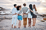 Rear view of a Unknown group of friends enjoying their time together at the beach. Diverse group of friends huddling outdoors