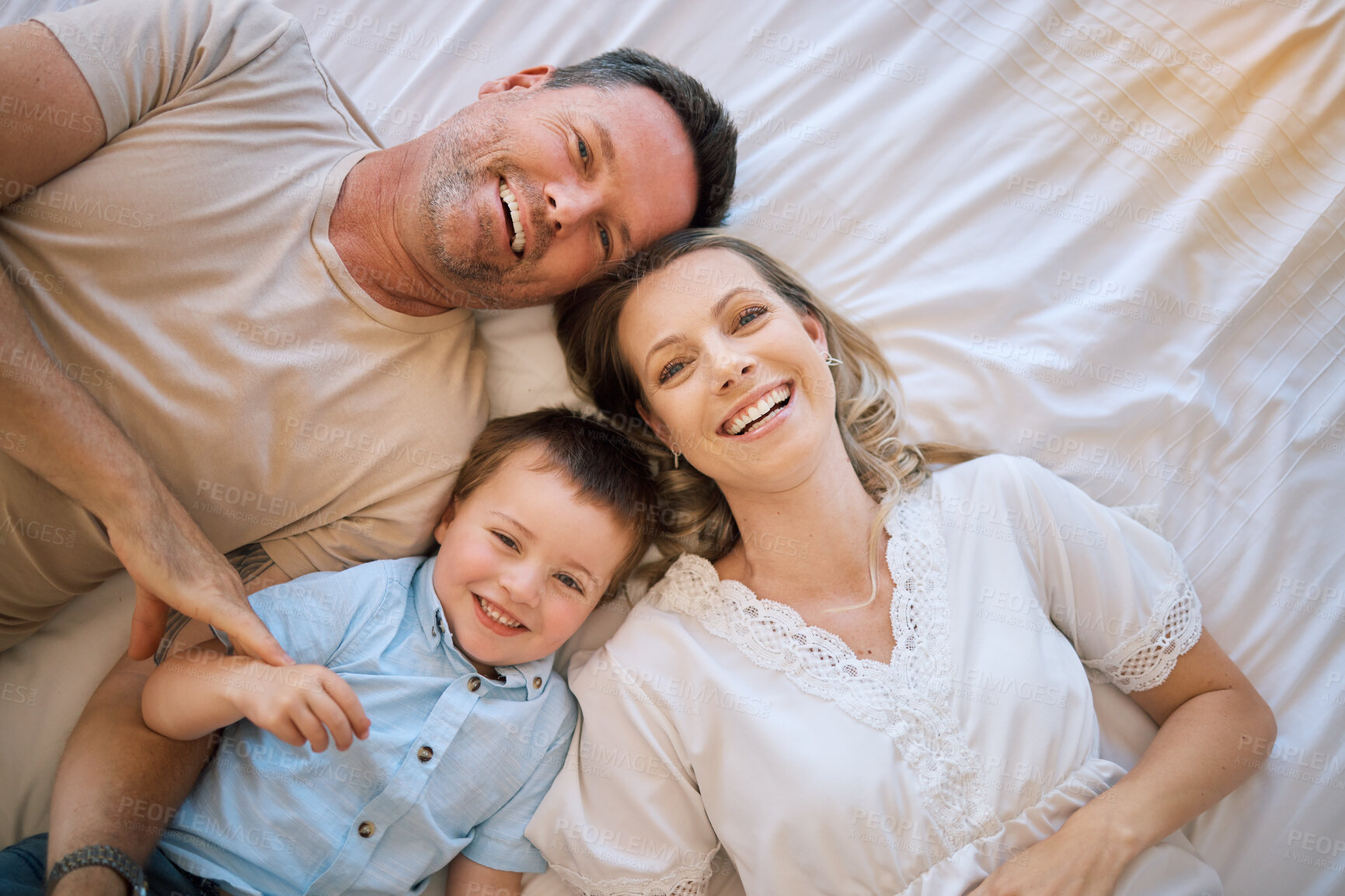 Buy stock photo Happy family, portrait and lying with child above on bed for bonding, holiday or weekend at home. Top view of mother, father and son with smile or relax in bedroom for morning, rest or joy at house