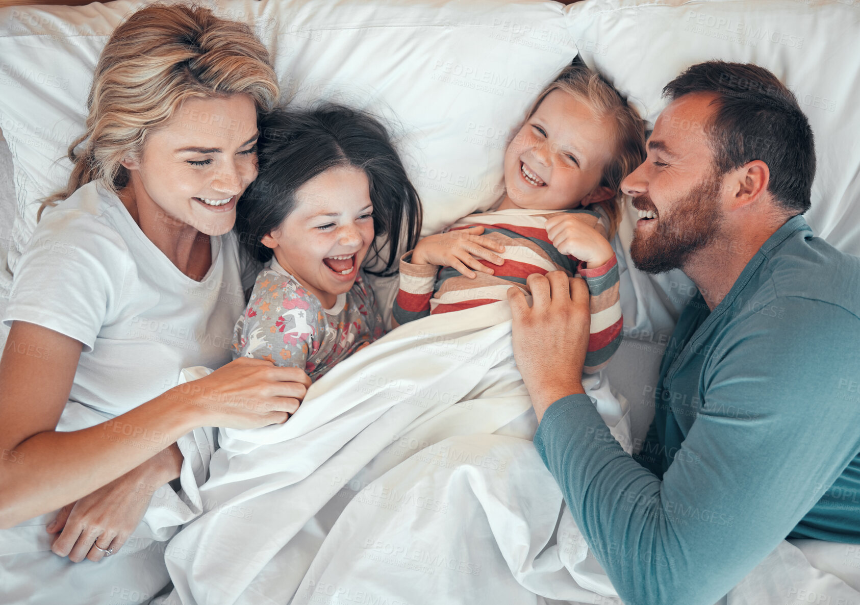 Buy stock photo Parents, children and laughing in bed with playing for funny game, wake up or bonding in morning. Top view, family and people with relax in blankets for love, wellness or security in bedroom of house