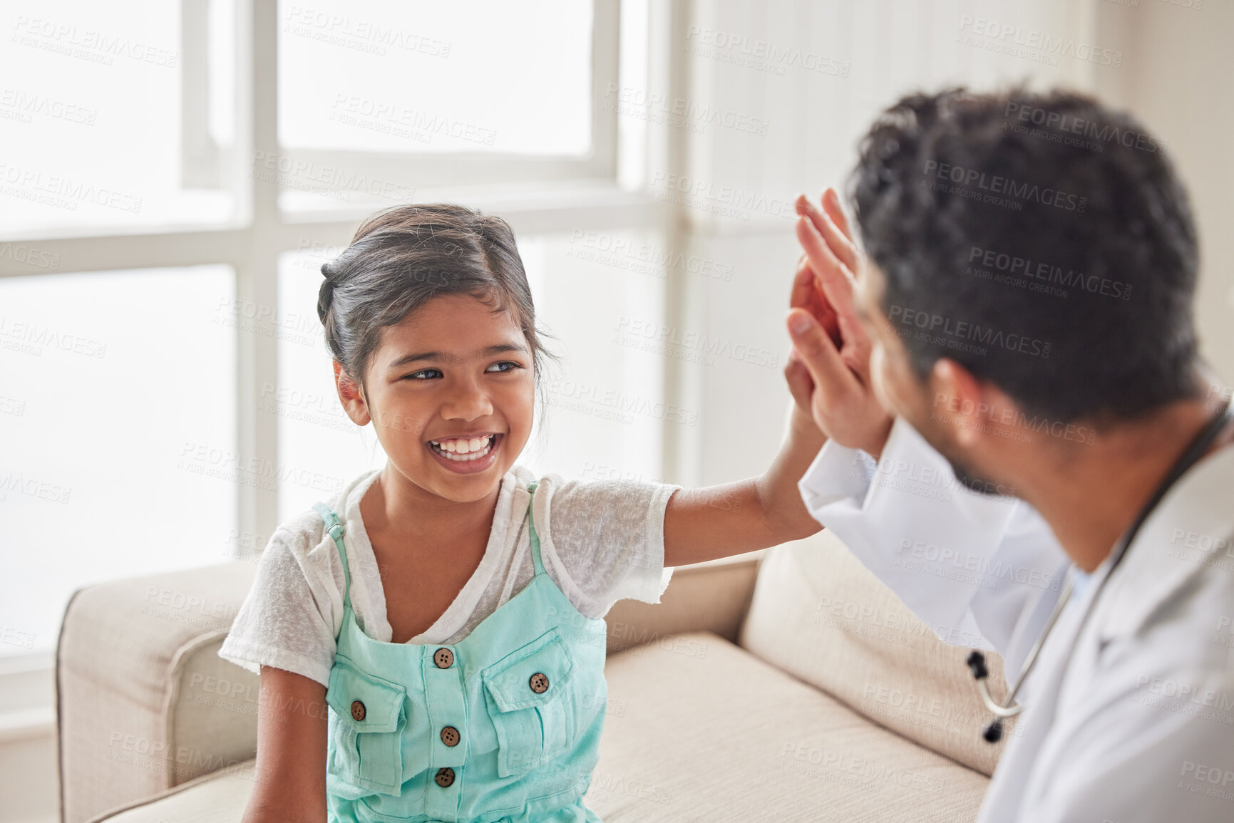 Buy stock photo Doctor, girl and high five in home, happy and excited with support for results with wellness on sofa. Pediatrician, man and child at family house, cheers and celebration for good news in Indonesia