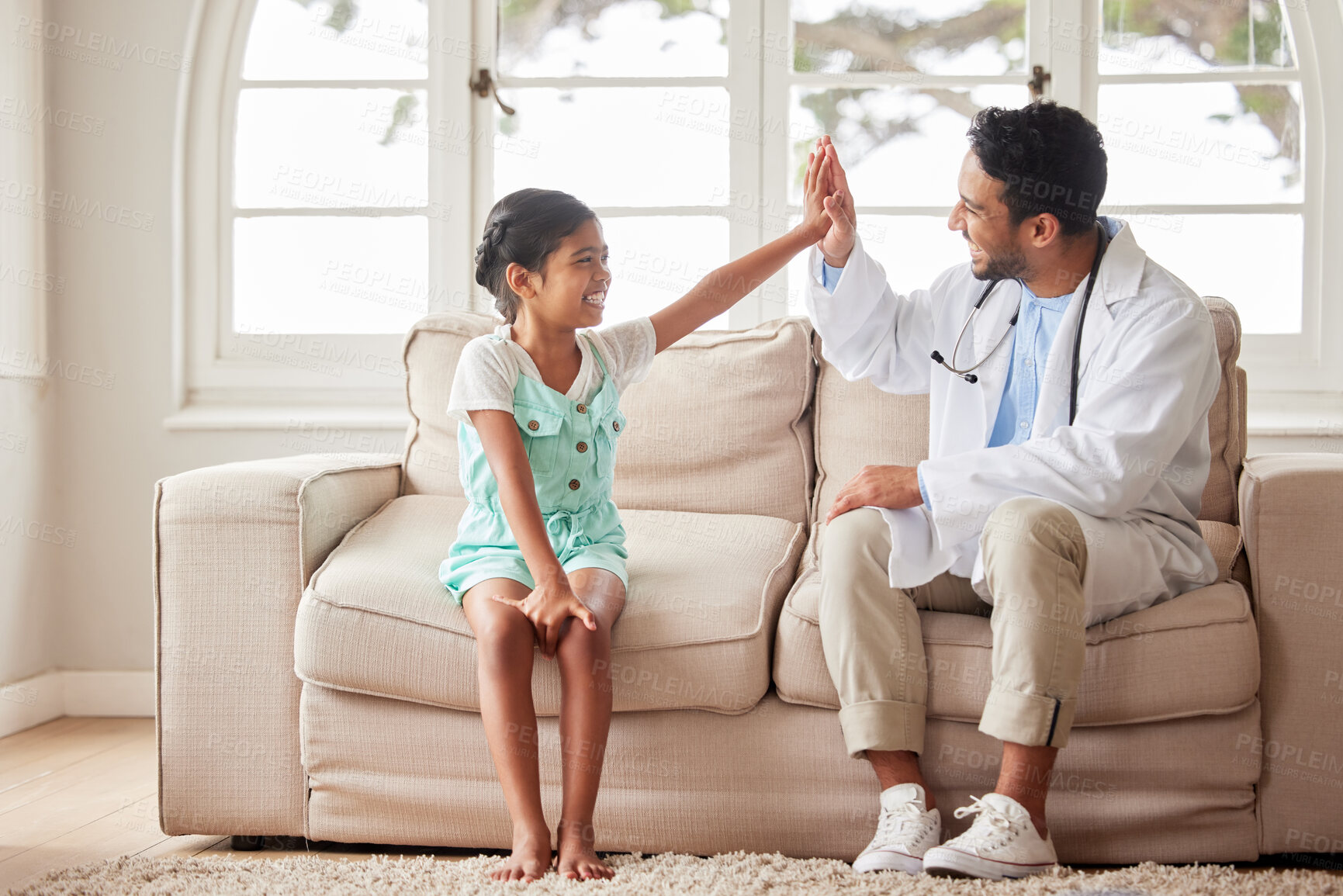 Buy stock photo Doctor, girl and high five in home, health or support for results, wellness or happy for recovery. Pediatrician, man and child on sofa at family house, cheers or celebrate for good news in Indonesia