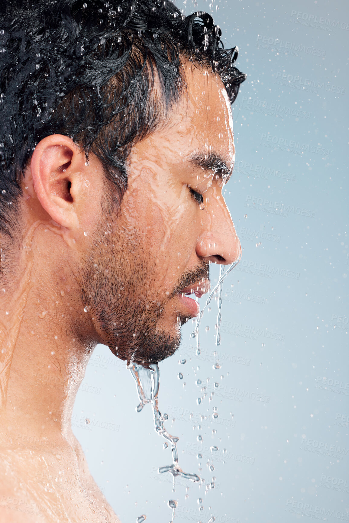 Buy stock photo Man, water drop and shower for cleaning in studio, hygiene and grooming on blue background. Male person, pamper and liquid for skincare in profile, cosmetics and washing for self care or treatment