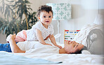 A baby girl and mother having fun at home. Portrait of a cute little child lying on the stomach of her parent. Young woman playing with her daughter