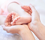 Mother holding baby feet. Closeup of tiny newborn baby feet held by a parent. Small baby toes. Little baby lying on a bed. Woman holding feet of little baby girl. Innocent infant being held by mother