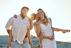 Carefree caucasian family walking and having fun together on the beach in summer. Parents giving their daughter and son a piggyback on holiday. Little siblings relaxing with their parents on vacation