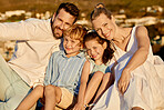 Carefree caucasian family watching the sunset together on the beach. Loving parents spending time with their son and daughter on holiday. Little siblings bonding with mom and dad on vacation