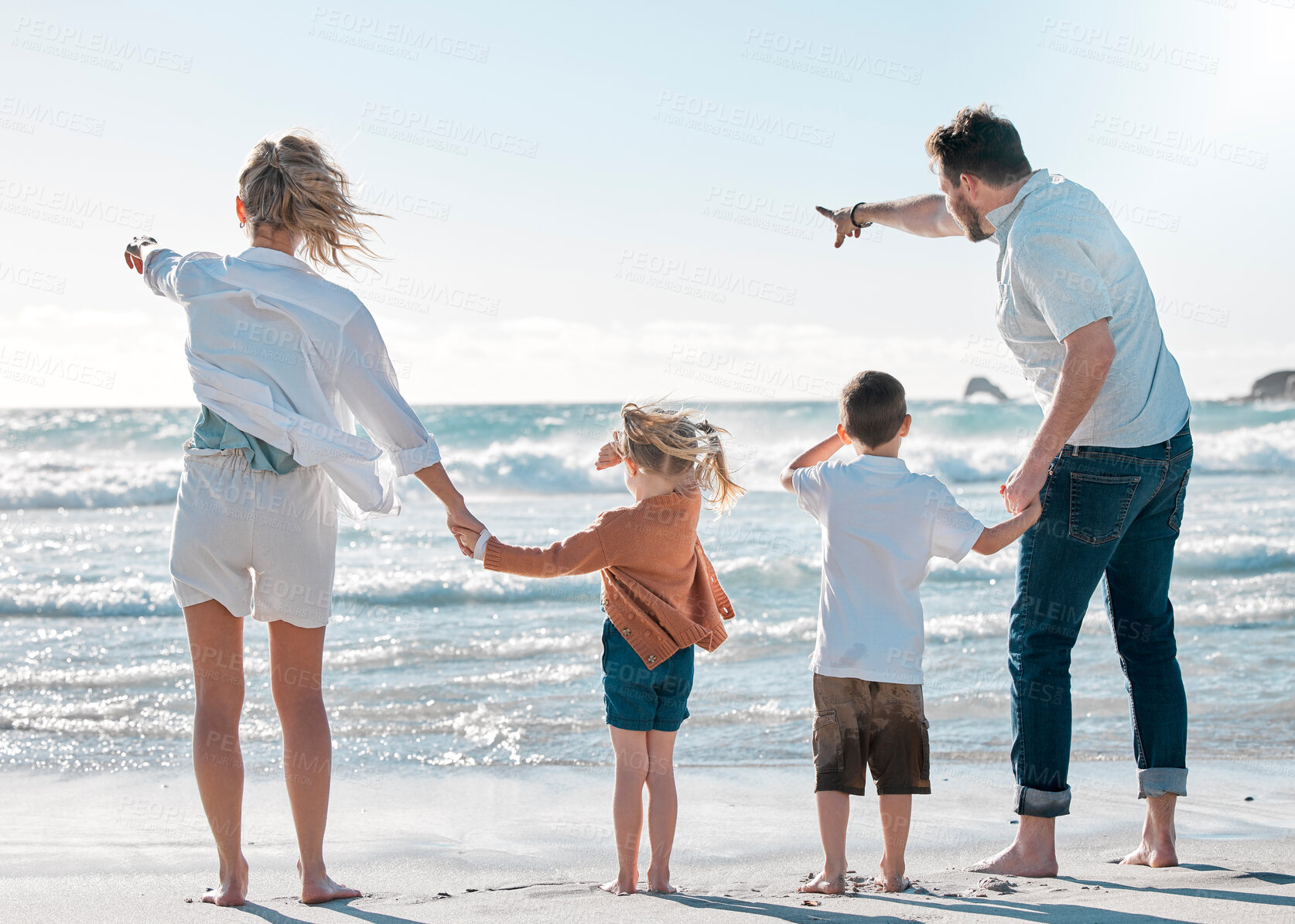 Buy stock photo Mom, dad and kids holding hands on beach for holiday adventure together on tropical island with waves. Mother, father and children on ocean vacation with travel, pointing and family bonding from back