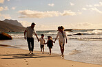 Carefree caucasian family holding hands and running together on the beach. Parents spending time with their son and daughter on holiday. Little siblings on a walk with their parents on vacation